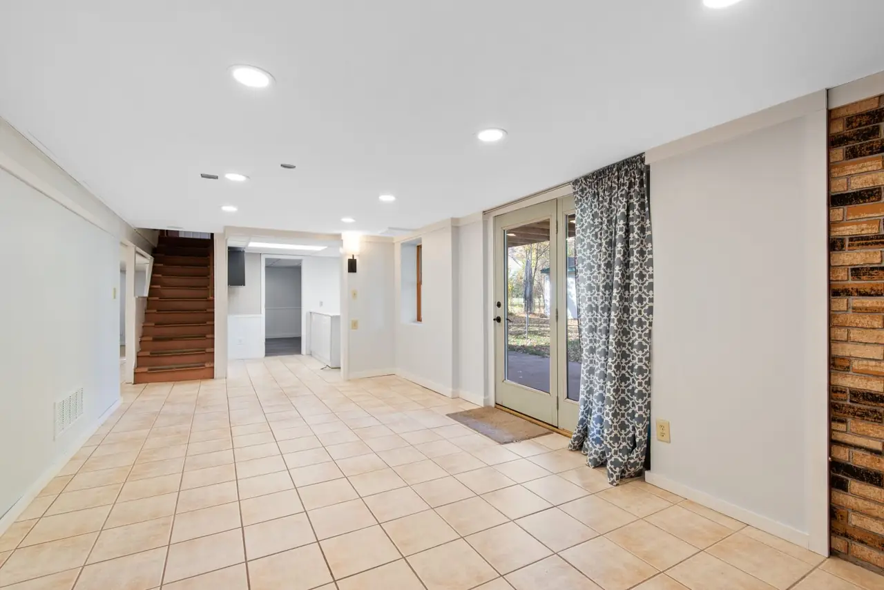 Sous-sol vide avec carrelage et portes vitrées.